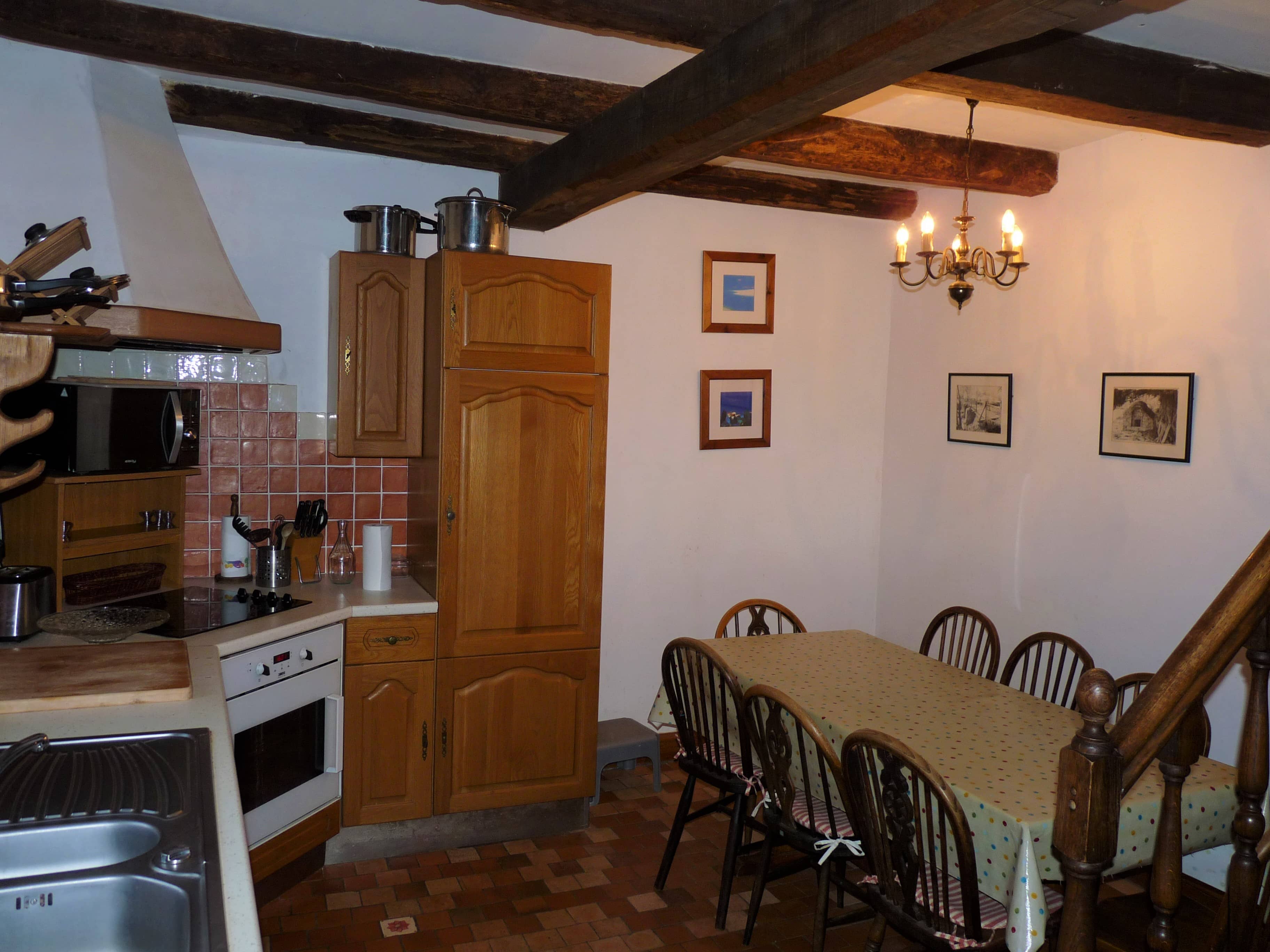 Kitchen of La Julerie cottage in Brittany, France, with a dining table, high-end appliances, and a view of the garden. Ideal for preparing holiday meals with family or friends.